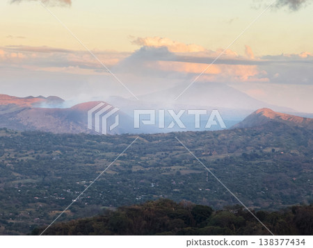 View of smoke rising from hills in the sunset over a valley 138377434