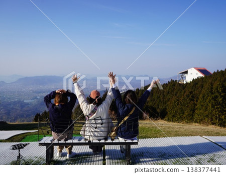 A woman sitting on a bench and looking at the scenery. 138377441