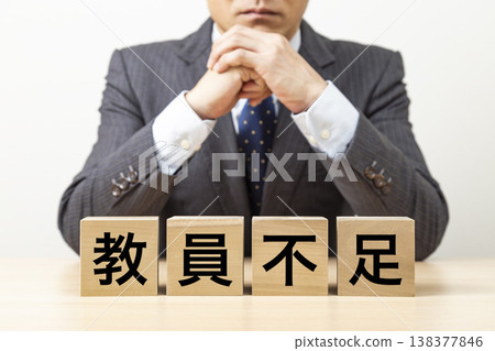 一塊寫著「教師短缺」字樣的磚塊和一個商人 一塊寫著「教師短缺」字樣的磚塊和一個商人 138377846