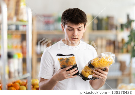 European guy looks at product and shop around, choose and buy pasta items in shop 138378428
