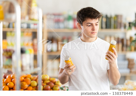 Guy choosing smoothie in bottles in grocery store Guy choosing smoothie in bottles in grocery store 138378449