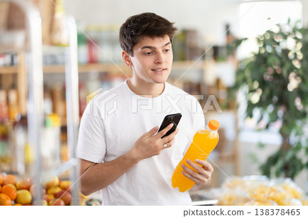 Guy scanning QR code on soft drink bottle in supermarket 138378465