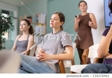 Female students are sitting in study room. Coach speaker telling in background. 138378481