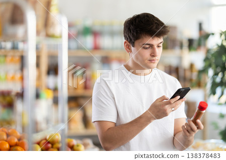 Male shopper scanning QR code on ground pepper label in grocery department of supermarket Male shopper scanning QR code on ground pepper label in grocery department of supermarket 138378483