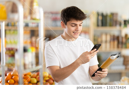 Young shopper using mobile app to pay for spaghetti in grocery store Young shopper using mobile app to pay for spaghetti in grocery store 138378484