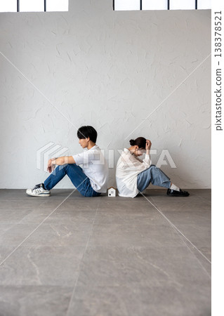 一對年輕男女背靠背坐著,中間放著一個房子形狀的裝飾品,他們若有所思,心事重重。 一對年輕男女背靠背坐著,中間放著一個房子形狀的裝飾品,他們若有所思,心事重重。 138378521