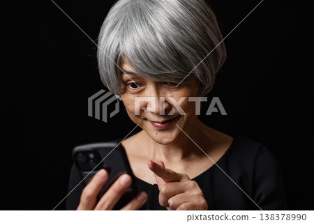 一位白髮蒼蒼的老婦人正在操作智慧型手機。 138378990