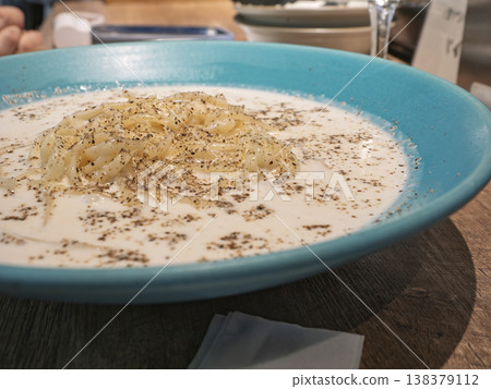 A rich, creamy pasta with plenty of black pepper, served in a beautiful blue bowl, bursting with flavor and a kick from the spices. A rich, creamy pasta with plenty of black pepper, served in a beautiful blue bowl, bursting with flavor and a kick from the spices. 138379112