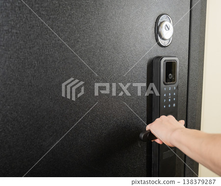 A woman opens a modern smart door lock with a digital keypad and biometric fingerprint access. A woman opens a modern smart door lock with a digital keypad and biometric fingerprint access. 138379287