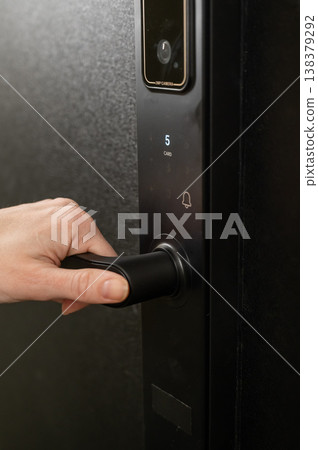 A woman opens a modern smart door lock with a digital keypad and biometric fingerprint access. A woman opens a modern smart door lock with a digital keypad and biometric fingerprint access. 138379292