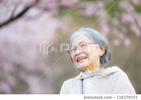 一位老婦人在櫻花樹下,花瓣飄落,面帶微笑,讓人聯想起春天裡健康快樂的景象;一位老婦人在賞櫻時仰望著櫻花。 一位老婦人在櫻花樹下,花瓣飄落,面帶微笑,讓人聯想起春天裡健康快樂的景象;一位老婦人在賞櫻時仰望著櫻花。 138379355