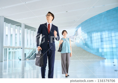 一對商務人士自信地大步穿過辦公大樓大廳。 138379706