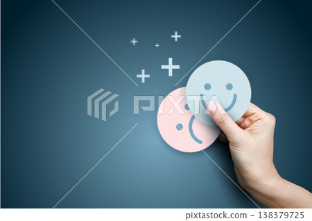 Hand covering sad face with happy smiling face icon on blue background. Concept of mindset shift, positive thinking, excellent customer satisfaction feedback, mood improvement, and mental health. Hand covering sad face with happy smiling face icon on blue background. Concept of mindset shift, positive thinking, excellent customer satisfaction feedback, mood improvement, and mental health. 138379725