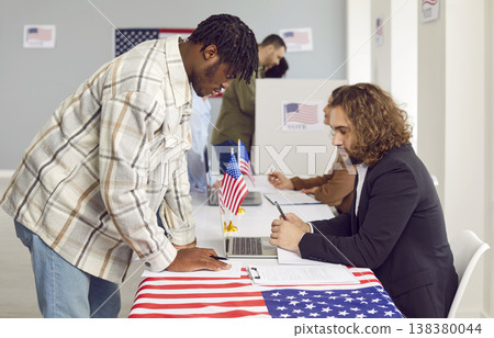 Side view portrait of a man registering at polling station with American flags on election day. Side view portrait of a man registering at polling station with American flags on election day. 138380044