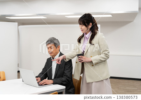 一位女員工正在向辦公室裡的一位男士解釋某件事。 138380573