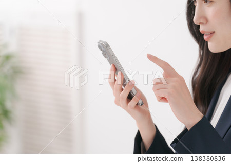 操縱智能手機的衣服的一名婦女 138380836