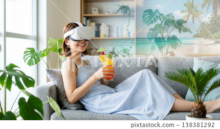 一位微笑的女士在家中享受虛擬實境度假之旅。虛擬實境體驗搭配熱帶雞尾酒。 138381292