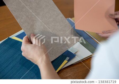 A young couple holds wallpaper samples in their hands as they discuss the issue. 138381719