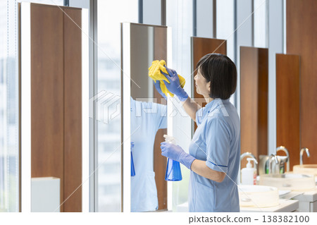 Middle-aged female cleaning staff wiping surfaces. Middle-aged female cleaning staff wiping surfaces. 138382100
