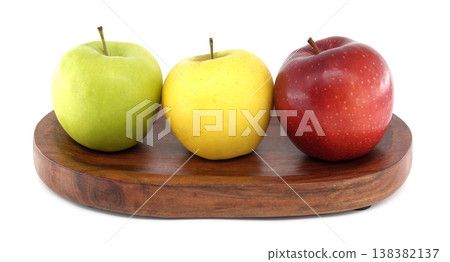 Three colorful apples, green, yellow, and red, arranged on a wooden board Three colorful apples, green, yellow, and red, arranged on a wooden board 138382137