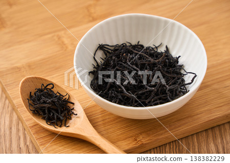 Dried hijiki seaweed, a Japanese food ingredient served in a small white bowl. 138382229