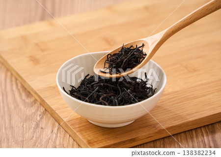 Dried hijiki seaweed, a Japanese food ingredient served in a small white bowl. 138382234