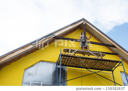 Front angle of home with visible scaffolds and unfinished decorative trim, residential architecture with timber work underway. 138382637