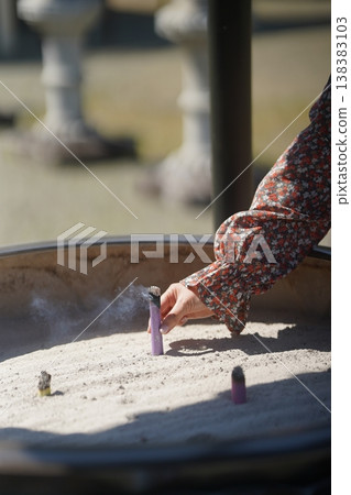 A woman's hand offering incense at a temple 138383103