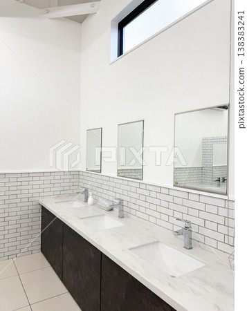 A shared toilet space with multiple sinks, predominantly decorated in white. A shared toilet space with multiple sinks, predominantly decorated in white. 138383241