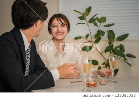 A smiling couple enjoying champagne or sparkling wine at their dining table at home. 138383338