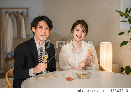 一對笑容滿面的夫婦在家中的餐桌旁享用香檳或氣泡酒。 138383340