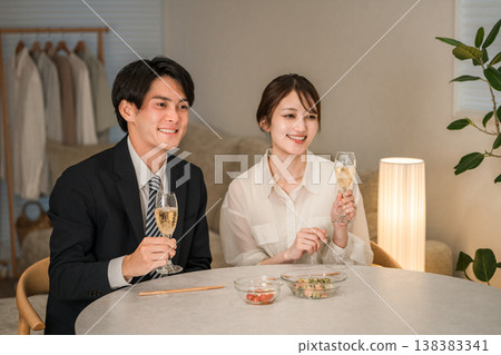 一對笑容滿面的夫婦在家中的餐桌旁享用香檳或氣泡酒。 138383341