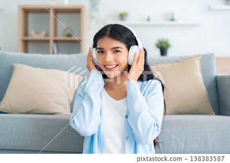 Young asian woman listening to music on couch in living room at home Young asian woman listening to music on couch in living room at home 138383587