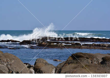 白色的海浪猛烈地拍打著福島縣磐城市名立海岸的岩石海岸、礁石和飛濺的浪花。 138383807
