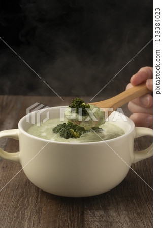 用湯匙舀起熱氣騰騰的青花菜湯。 138384023
