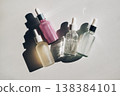Skincare liquids and oils in glass dropper bottles on white surface, creating interesting shadows 138384101