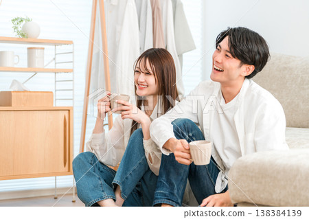 一對年輕的亞洲夫婦在家裡的客廳看電視。 138384139
