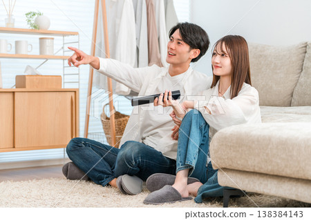 Young Asian couple watching TV in the living room at home Young Asian couple watching TV in the living room at home 138384143