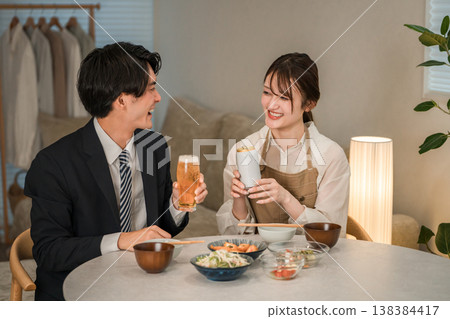 一對年輕的亞洲夫婦(啤酒,罐裝啤酒)在家裡的餐桌上吃喝。 一對年輕的亞洲夫婦(啤酒,罐裝啤酒)在家裡的餐桌上吃喝。 138384417