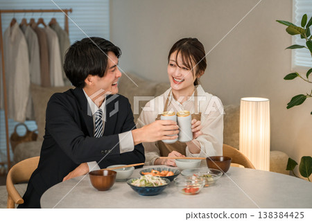 一對年輕的亞洲夫婦(啤酒,罐裝啤酒)在家裡的餐桌上吃喝。 一對年輕的亞洲夫婦(啤酒,罐裝啤酒)在家裡的餐桌上吃喝。 138384425
