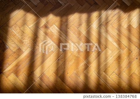 Warm wooden parquet floor with diagonal sunlight casting shadows in a herringbone pattern Warm wooden parquet floor with diagonal sunlight casting shadows in a herringbone pattern 138384768