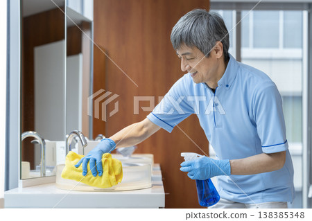 一名資深男性清潔工正在擦拭水槽。 一名資深男性清潔工正在擦拭水槽。 138385348