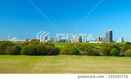 A winter morning view from the embankment of the Edogawa River, showing a soccer field and buildings near Misato-Chuo Station on the opposite bank (with Mount Fuji in the distance). 138385718