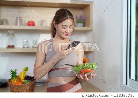 Young woman photographing healthy salad in modern kitchen Young woman photographing healthy salad in modern kitchen 138385785