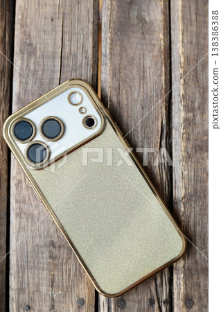 A triple-camera smartphone with a gold glitter back case. 138386388