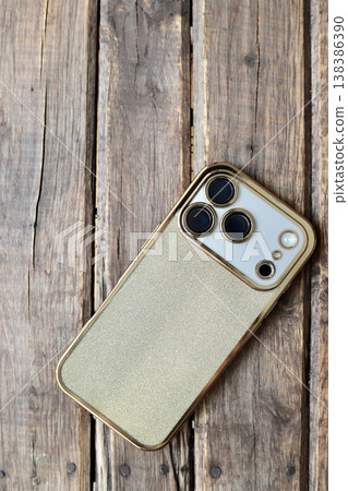 A triple-camera smartphone with a gold glitter back case. 138386390