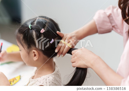 Mother braiding daughter's hair for school preparation Mother braiding daughter's hair for school preparation 138386516