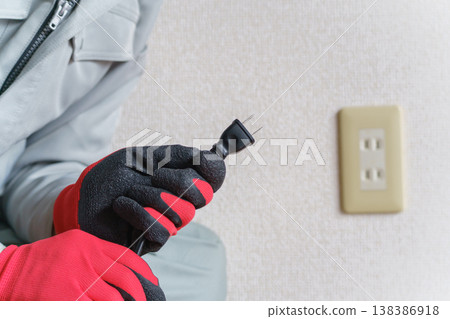 一名工人手持插頭和電源插座。 一名工人手持插頭和電源插座。 138386918