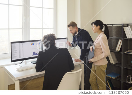 Business team analyzing finance charts on dual monitors during office meeting Business team analyzing finance charts on dual monitors during office meeting 138387060