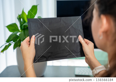 Person holding plain unbranded parcel without label at home. Generic packaging for ecommerce shipping and delivery concept with copy space. 138388184